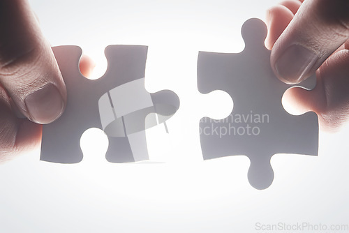 Image of Puzzle, teamwork and synergy with hands of person on white background for achievement, solution or development. Mission, game and cooperation with of jigsaw piece for support, success and integration