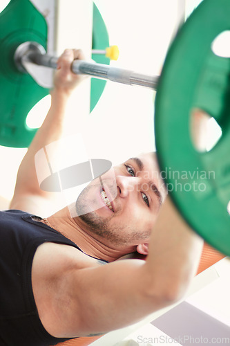Image of Man, portrait and weightlifting in a gym with athlete wellness and smile from workout. Fitness, happy bodybuilder and male person with weights power from strong arm muscle and training at health club