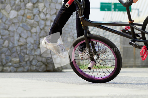 Image of Legs, wheel and person on bicycle for trick, challenge and action at skatepark in city. Closeup, cycling stunt and urban biker in town with skill for balance, performance risk and freedom of motion