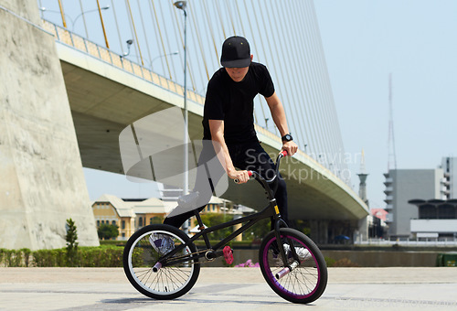 Image of Urban cycling, trick and man on bicycle for sports, balance and action in city street. Cool male person, cycle stunt and control of biker in town for skill, performance and freedom of motion outdoor