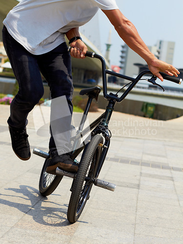 Image of Bike, trick and closeup of man outdoor for sports, balance and action at urban skatepark. Male person, bicycle stunt and control on cycling wheels in city for skill, performance and freedom of motion