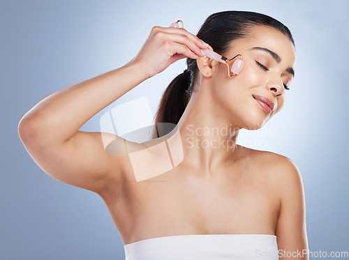 Image of Skincare, derma roller and asian woman in studio for anti aging, cosmetic or face massage on grey background. Rose quartz, facial and female wellness model relax with microneedling, beauty or routine