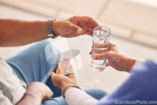 Image of Hands with pills, old man and nurse with water for supplements, support and help at nursing home. Medicine, senior care and caregiver with sick patient, tablet and glass for healthcare in retirement