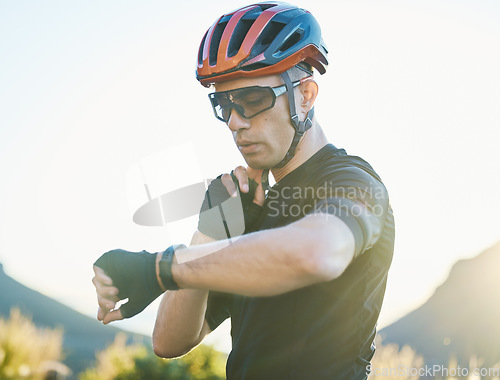 Image of Watch, nature and cyclist checking his pulse while cycling for fitness or exercise on a mountain. Sports, bicycle and young male athlete with time for heart rate while training for a race or marathon