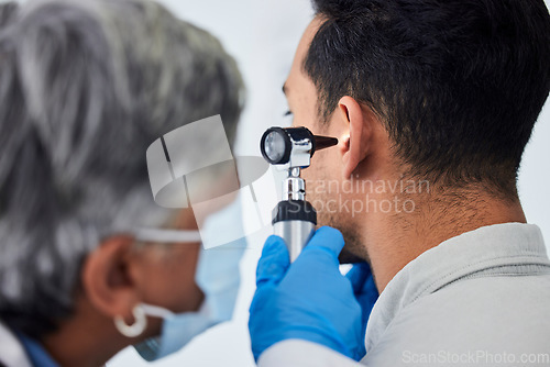 Image of Woman, doctor and checking patient ear for flu, exam or healthcare appointment at the hospital. Female person or medical professional with protection looking at ill or sick man with flu at the clinic