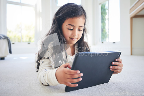 Image of Young girl, tablet and game app or cartoon streaming online with internet, elearning and relax on carpet in house. Watch animation film, female kid at home and website, entertainment and subscription