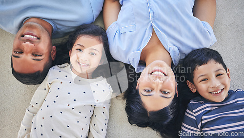 Image of Above, portrait and happy family on a floor relax, bond and playing in their home on the weekend. Face, smile and top view of children with young parents in a bedroom with love, fun and chilling