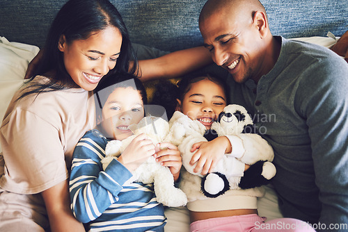 Image of Parents, children and family in a bed together with love, care and security for comfort. Woman, man and kids with a teddy bear and happy smile for quality time in a home bedroom to relax from above