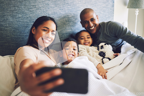 Image of Parents, children or family selfie in a bed together with love, care and security or comfort. Woman, man and kids with a happy smile for quality time or profile picture in a home bedroom to relax