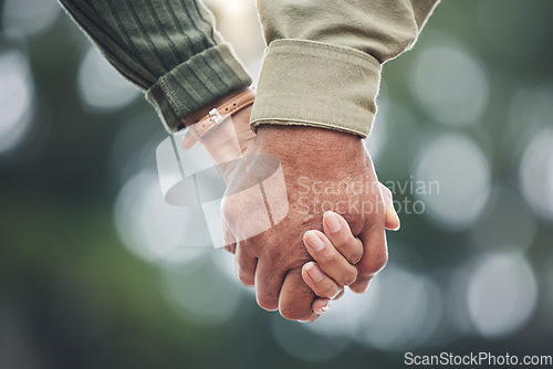 Image of Love, holding hands and couple together in partnership, marriage or people with trust, bonding or moment in nature with bokeh background. Hand, support and unity with a soulmate or romantic partner
