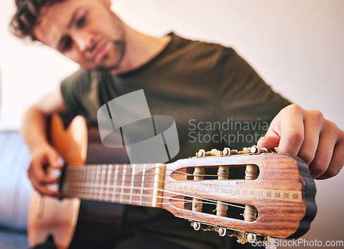 Image of Closeup, man and tuning guitar for music, talent and creative skill of sound production in home studio. Hands, musician and singer check notes of acoustic instrument for audio, performance and artist