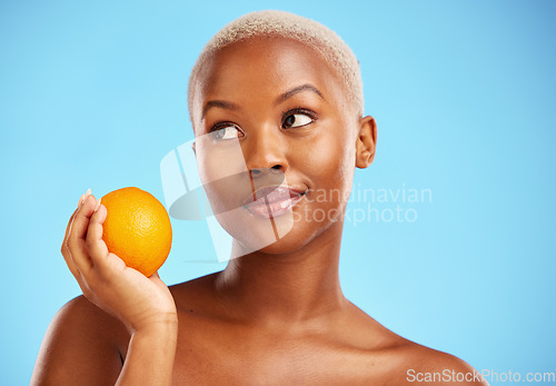 Image of Orange, thinking and black woman with skincare, natural beauty and vitamin c against a blue studio background. Female person, ideas and model with citrus fruit, health and wellness with dermatology