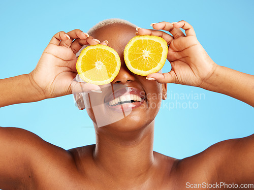Image of Orange, beauty and smile with a model black woman in studio on a blue background for a facial. Food, skincare and natural with a happy young female person holding a snack for health or wellness