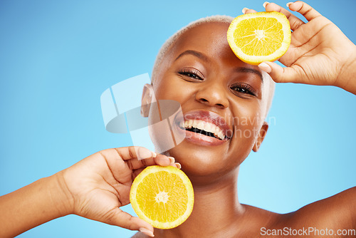 Image of Portrait, orange and beauty with a model black woman in studio on a blue background for nutrition. Smile, fruit and skincare with a happy young person holding a snack for natural health or wellness