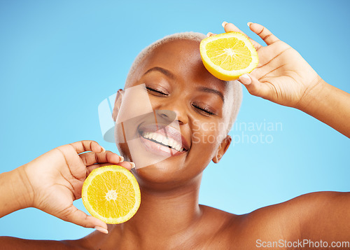 Image of Orange, face and nutrition with a model black woman in studio on a blue background for treatment. Beauty, skincare and smile with a happy young person holding natural fruit for health or wellness