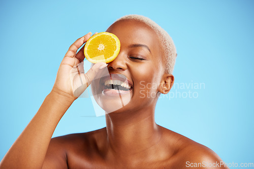 Image of Orange, beauty and funny with a model black woman in studio on a blue background for natural nutrition. Fruit, skincare and smile with a happy young female person laughing for health or wellness
