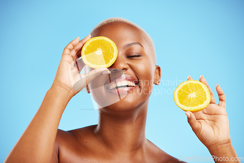 Image of Skincare, orange and smile with a model black woman in studio on blue background for treatment. Face, beauty and fruit with a happy young female person holding a slice for natural health or wellness