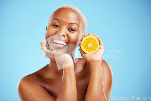 Image of Portrait, beauty and orange with a black woman in studio on a blue background for fruit nutrition. Smile, skincare or diet with a happy young female person holding food for natural health or wellness