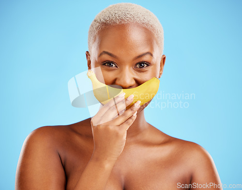 Image of Black woman, banana and mouth for potassium, vitamin or fiber against a blue studio background. Portrait of happy African female person with organic fruit smile for health or wellness on mockup space