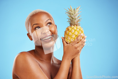 Image of Happy black woman, pineapple and thinking for diet or natural nutrition against a blue studio background. Thoughtful African female person in wonder with organic fruit for vitamin, fiber or wellness