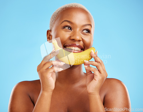 Image of Beauty, smile and banana with a model black woman thinking on a blue background in studio. Skincare, idea and food with a happy young female person holding yellow fruit for natural wellness or detox
