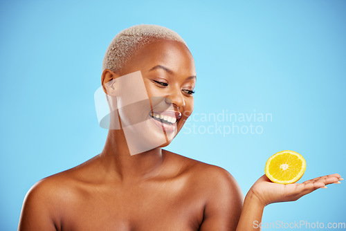 Image of Orange, beauty or health and a model black woman in studio on blue background with fruit in the palm of her hand. Natural, skincare or diet with a happy young person holding healthy food for wellness