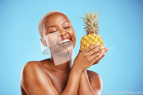 Image of Happy black woman, pineapple and diet for natural nutrition or health against a blue studio background. African female person smile in happiness holding organic fruit for vitamin, fiber or wellness