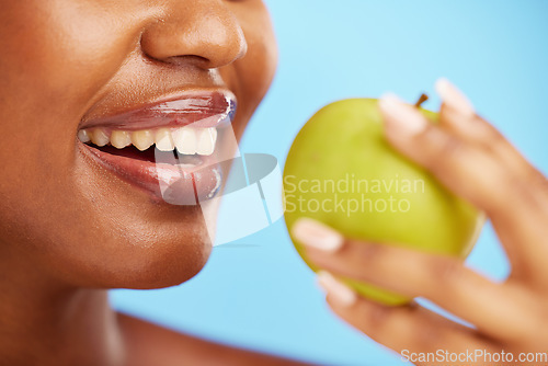 Image of Black woman, mouth and apple in diet, nutrition or health and wellness against a blue studio background. Closeup of African female person eating natural organic fruit for vitamin, fiber or food snack