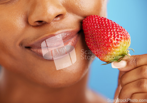 Image of Strawberry, lips and beauty woman for cosmetics, eco friendly product and color choice. Happy, mouth and skincare person or model, red fruit and dermatology or vegan makeup on studio blue background