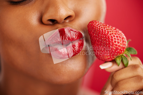 Image of Kiss, beauty and woman with strawberry on face with skincare or lips in red background or closeup. Cosmetics, wellness and nutrition with female or fruit in studio for detox and diet or self love.