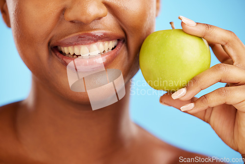 Image of Woman, smile and apple for diet, nutrition or health and wellness against a blue studio background. Closeup of female person mouth with natural organic green fruit for vitamin, fiber or food snack