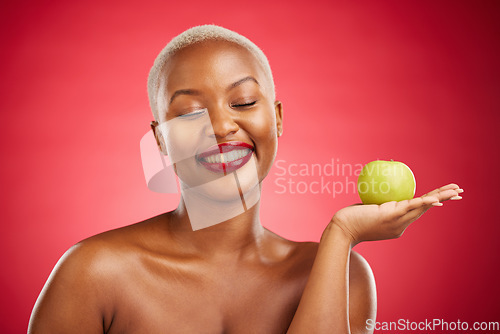 Image of Happy black woman, apple and natural nutrition for healthy diet against a red studio background. African female person smile with natural organic green fruit for food snack, health and wellness