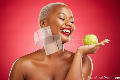 Image of Happy black woman, apple and natural nutrition for diet, health and wellness against a red studio background. African female person smile and palm with organic green fruit for food, snack or meal