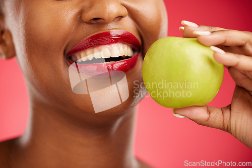 Image of Woman, mouth and apple in diet, nutrition or health and wellness against a red studio background. Closeup of female person smile with lipstick or natural organic fruit in vitamin, fiber or food snack