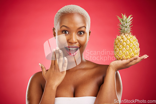 Image of Beauty, portrait and pineapple surprise with a woman in studio for healthy food, diet or fruit. Black person with makeup on red background for face wellness, natural cosmetics and wow skin care glow