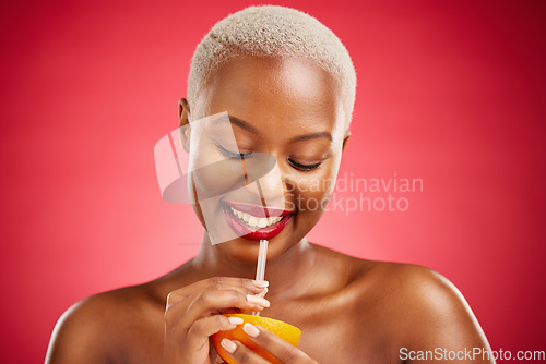 Image of Happy black woman, orange and vitamin C for diet or natural nutrition against a red studio background. African female person smile and drinking organic citrus fruit with straw on mockup space