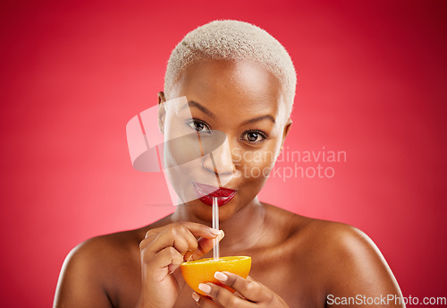 Image of Black woman, portrait and drinking orange for vitamin C, diet or natural nutrition against a red studio background. African female person with organic citrus fruit, juice and straw on mockup space