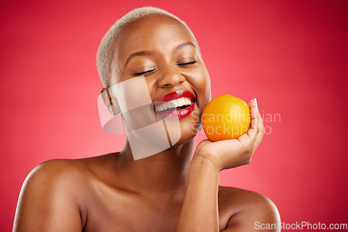 Image of Orange, smile and black woman with natural beauty, dermatology and vitamin c on a red studio background. Female person, happy or model with citrus fruit, health or wellness with cosmetics or skincare