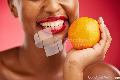 Image of Woman, mouth and orange for vitamin C, diet or health and wellness against a red studio background. Closeup of female person smile with lipstick and organic citrus fruit for snack, fiber or food