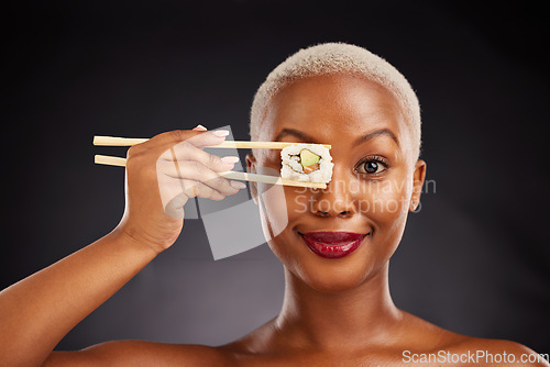 Image of Woman, face and sushi with chopsticks in studio for healthy eating, beauty and food. Portrait of a black female model with makeup on a dark background for wellness, diet or seafood advertising