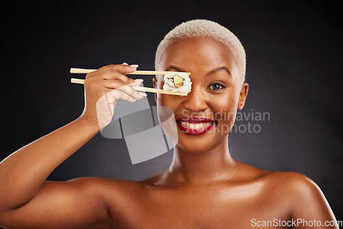 Image of Chopsticks, face and woman with sushi in studio for healthy eating, beauty and food. Portrait of a black female model with makeup on a dark background for wellness, diet or seafood advertising