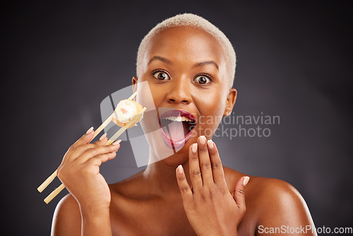 Image of Face, surprise and woman with sushi and chopsticks in studio for healthy eating, beauty or food. Black female model with makeup on dark background for wellness glow, wow diet or seafood portrait