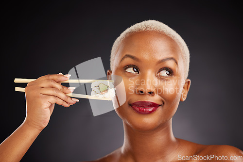 Image of Woman, thinking and sushi with chopsticks in studio for healthy eating, beauty and food. Face of a black female model with makeup on a dark background for wellness, diet or seafood advertising idea