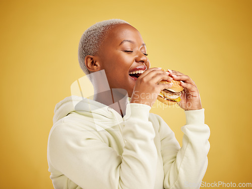 Image of Hamburger, eating and happy woman or student on a studio, yellow background for restaurant promotion or deal. Hungry and excited african person or customer experience with fast food and burger bite