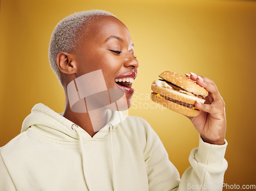 Image of Burger, eating and young woman or student on studio, yellow background for restaurant, lunch and youth discount. Hungry and excited african person or customer experience, fast food and hamburger bite