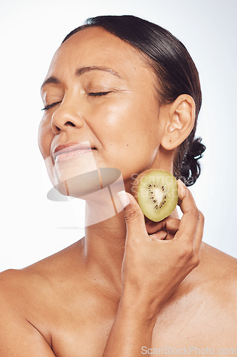 Image of Relax, beauty or mature woman with kiwi for healthy detox, skincare or facial treatment routine in studio. Spa, face or senior model with wellness, self love or fruit isolated on white background