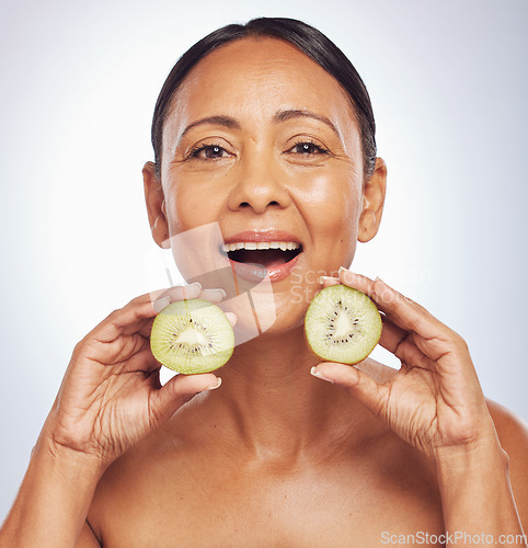 Image of Face, excited and mature woman with kiwi in studio isolated on a white background. Portrait, fruit and natural model with food for nutrition, skincare and diet for vitamin c, anti aging and health.