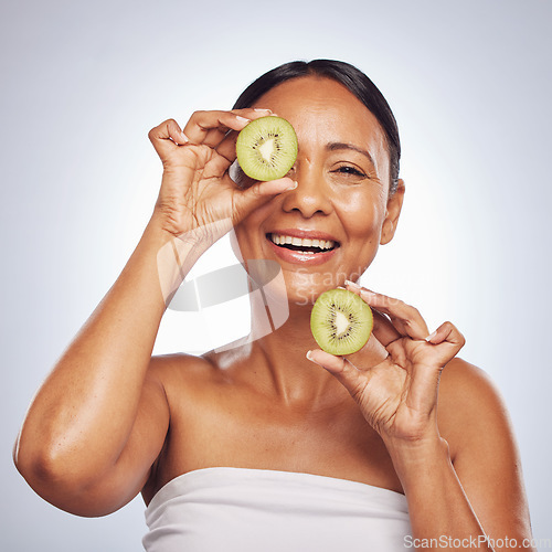 Image of Skincare, face and mature woman with kiwi in studio isolated on a white background. Food, natural fruit and portrait of happy model with nutrition for wellness, healthy diet and beauty for anti aging