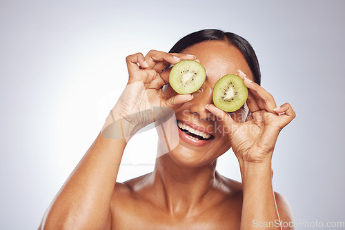 Image of Skincare, happy and senior woman with kiwi in studio isolated on a white background. Food, natural fruit and face of model with nutrition for wellness, healthy diet or vitamin c, anti aging or beauty