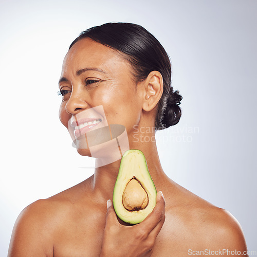 Image of Skincare, thinking and senior woman with avocado in studio isolated on a white background. Happy, natural fruit and mature model holding food for nutrition, healthy diet or omega 3 for anti aging.